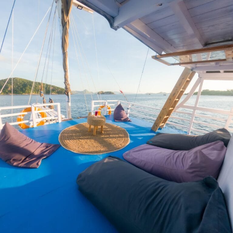 a deck of a boat with pillows and a table on the water